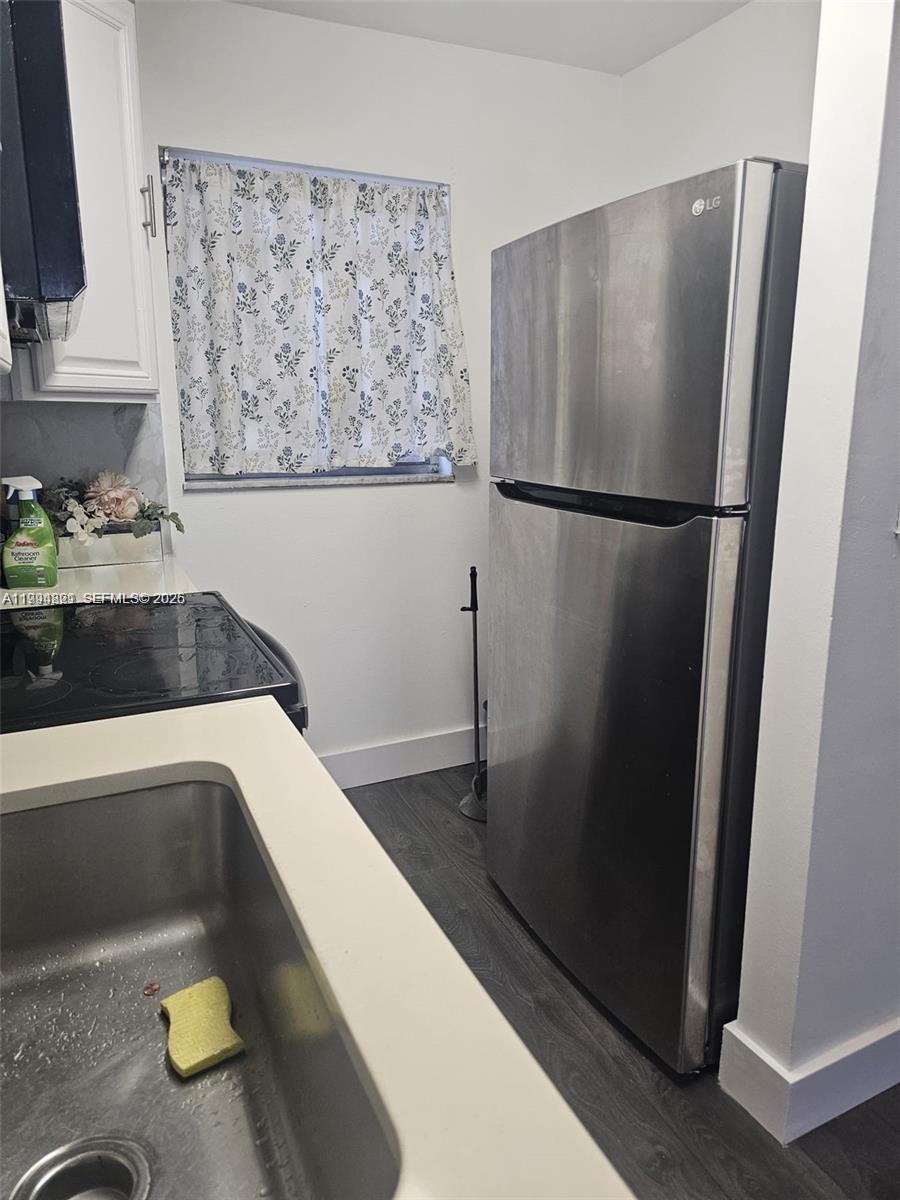 A kitchen features a stainless steel refrigerator, a sink, and a stovetop with white cabinets — 6055 W 19th # 209, Hialeah FL 33012, HIALEAH, FL