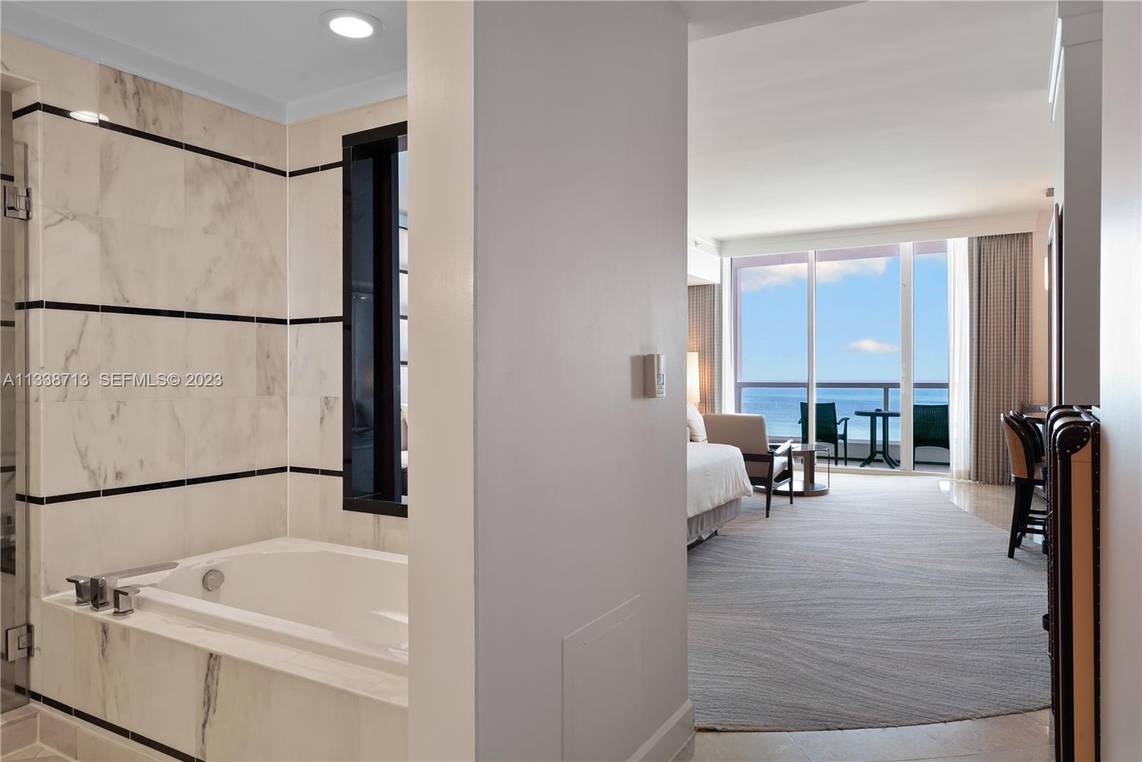 A marble-tiled bathroom with a soaking tub overlooks a bedroom with an oceanfront balcony — 4391 Collins Ave, Miami Beach FL 33140, MIAMI BEACH, FL