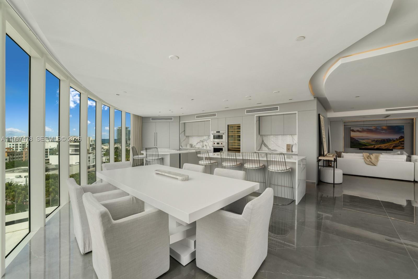 A modern open-plan kitchen and dining area features white surfaces, grey flooring, and floor-to-ceiling windows — 1000 S Pointe Dr # 901, Miami Beach FL 33139, MIAMI BEACH, FL