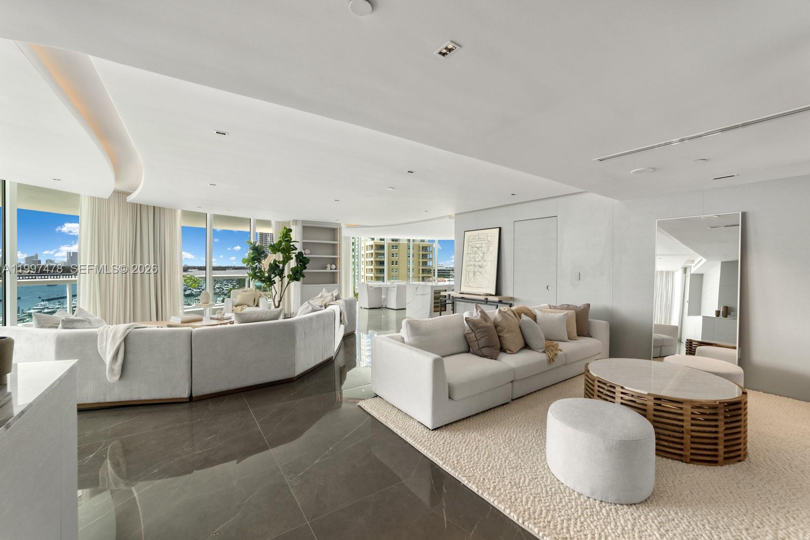 A modern living room features two white sectionals, dark tile flooring, and floor-to-ceiling windows — 1000 S Pointe Dr # 901, Miami Beach FL 33139, MIAMI BEACH, FL