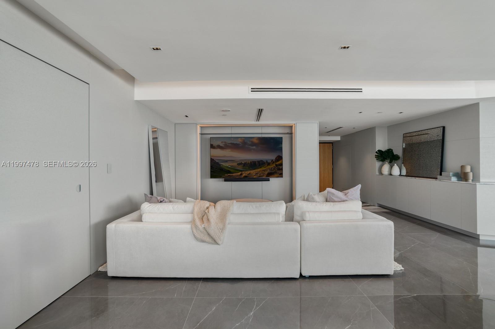 A modern living room features a white sectional sofa, a wall-mounted television, and tile flooring — 1000 S Pointe Dr # 901, Miami Beach FL 33139, MIAMI BEACH, FL