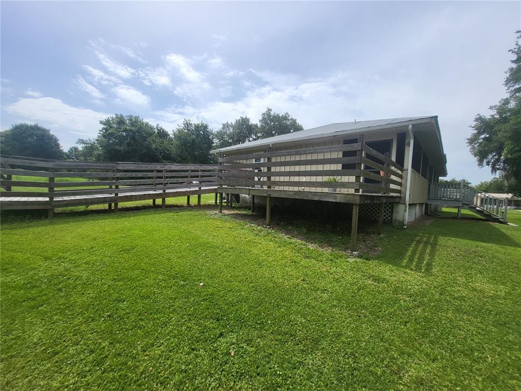 A house exterior features a long wooden wheelchair ramp leading to a raised deck — 32531 4TH AVENUE, SAN ANTONIO, FL