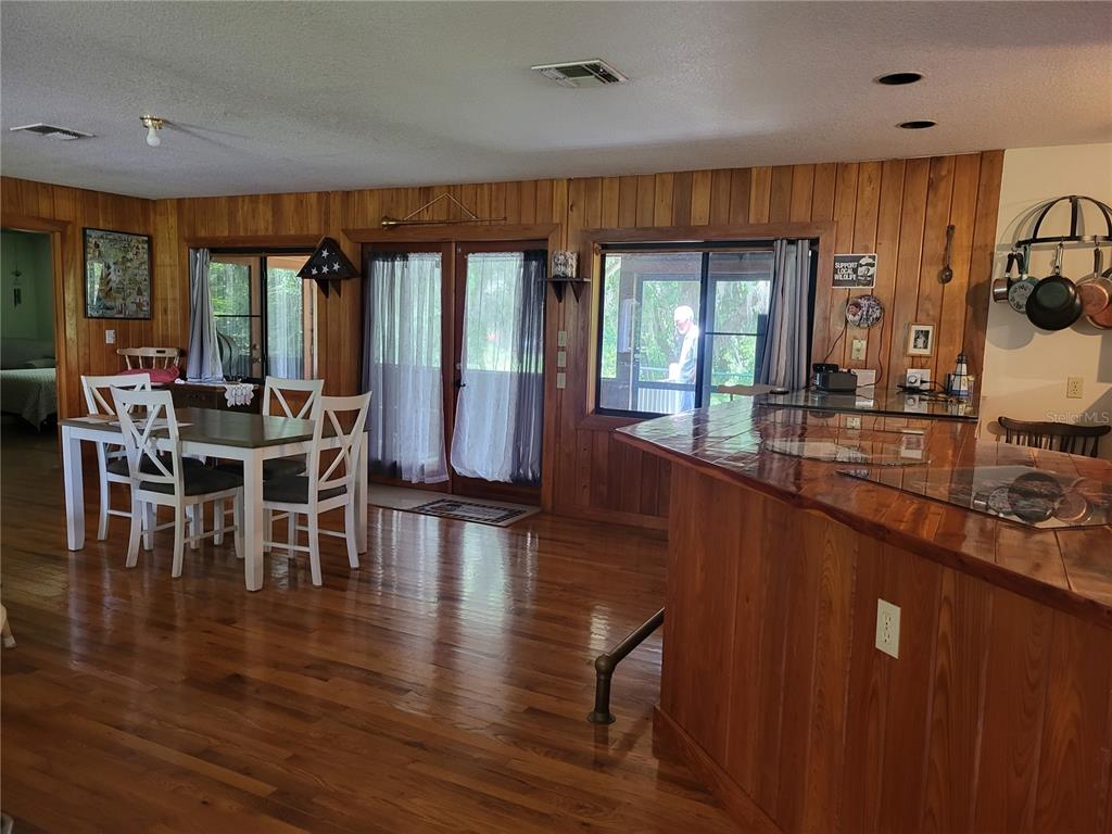 A dining area and kitchen with wood paneling, hardwood floors, and glass doors to a porch — 32531 4TH AVENUE, SAN ANTONIO, FL