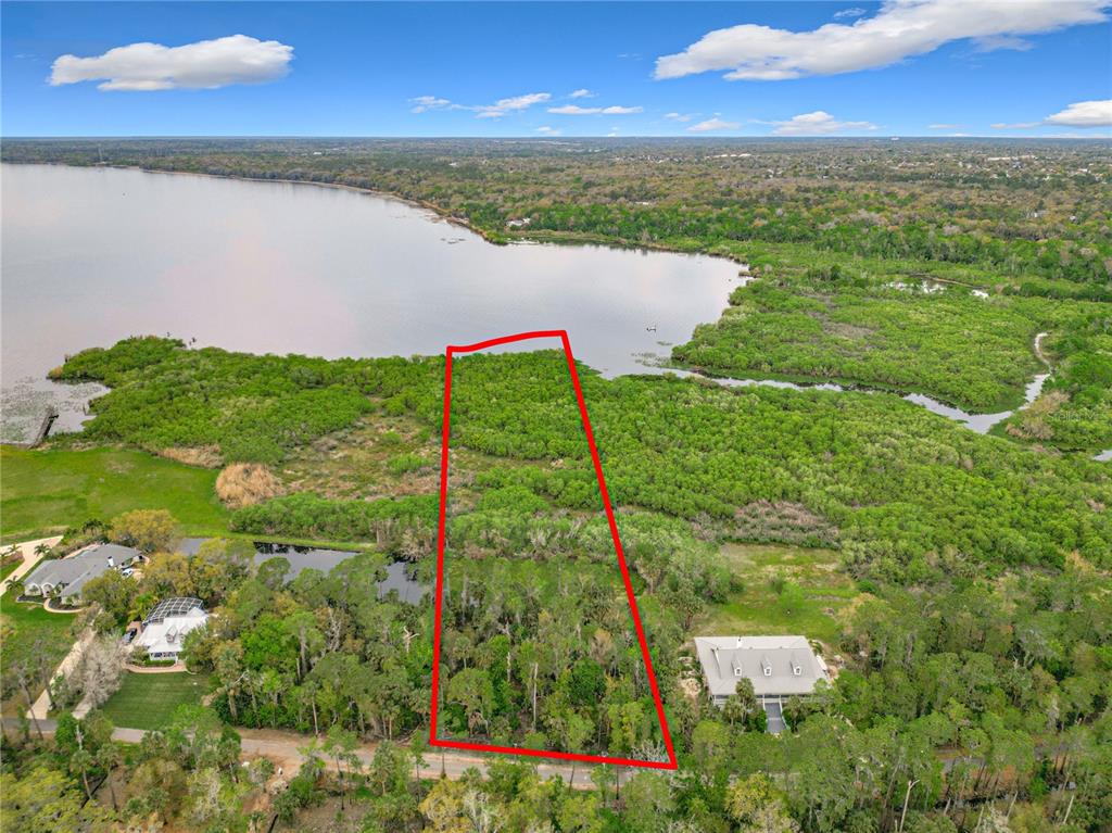 An aerial view shows a rectangular plot of land outlined in red near a lake — 1364 SIOUX TRAIL, DELTONA, FL