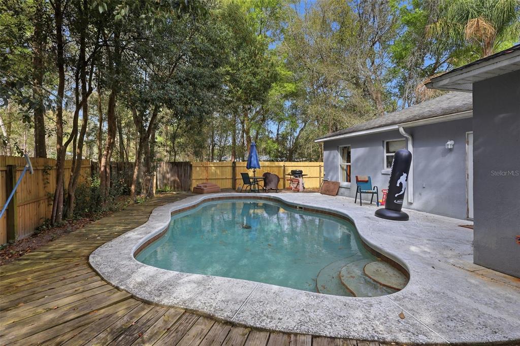 A backyard features a kidney-shaped swimming pool, a wooden deck, and a concrete patio area — 1496 10TH STREET, ORANGE CITY, FL