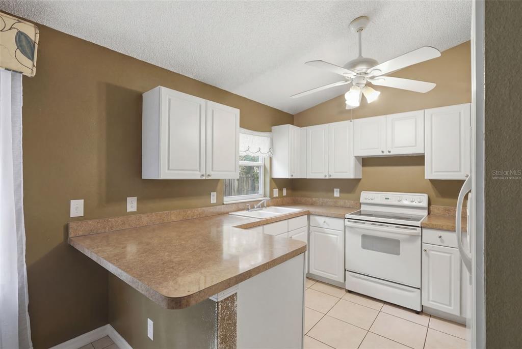 A kitchen with white cabinets, brown countertops, a white stove, and a ceiling fan — 1496 10TH STREET, ORANGE CITY, FL