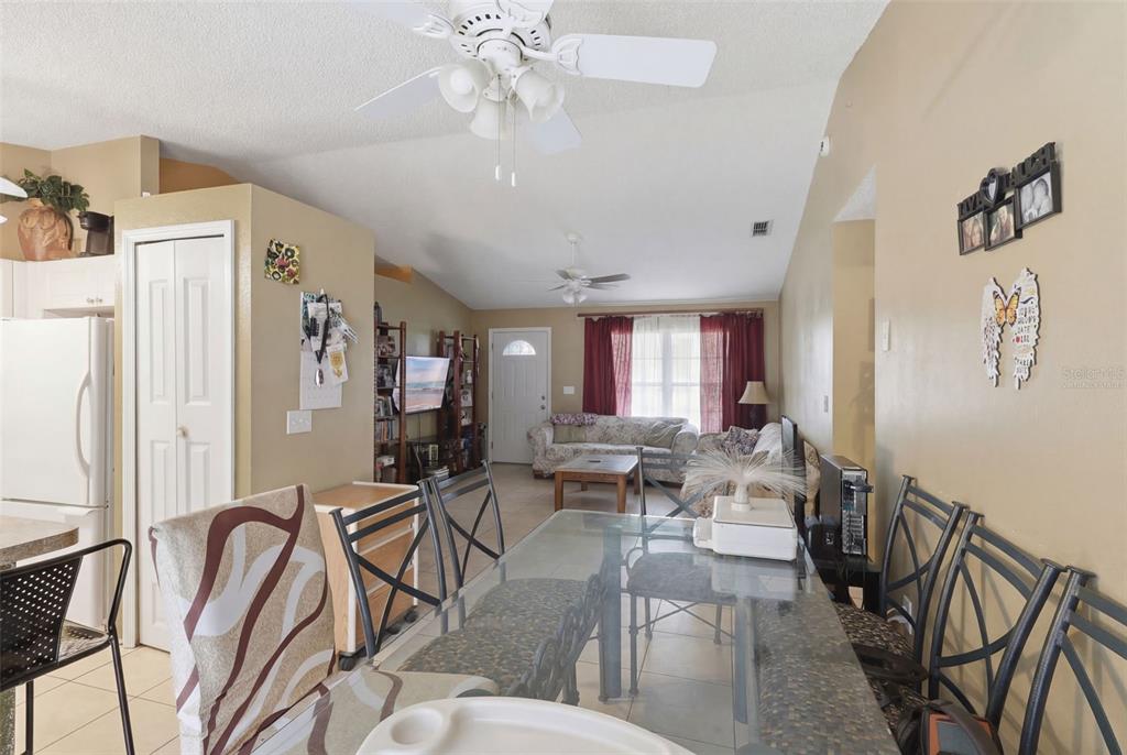 A dining area with a glass table leads into a living room with a ceiling fan — 1496 10TH STREET, ORANGE CITY, FL