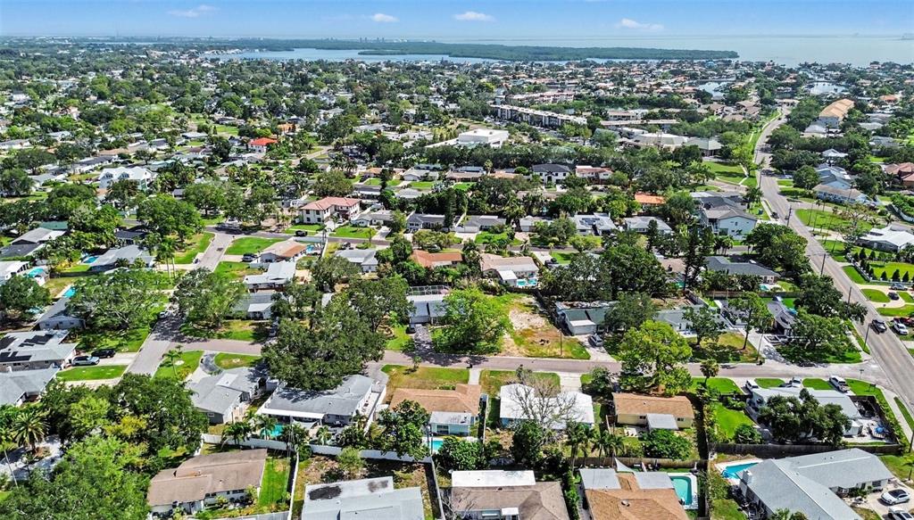 An aerial view shows a suburban neighborhood with houses, trees, and streets near the water — 1737 COLORADO AVENUE NE, ST PETERSBURG, FL