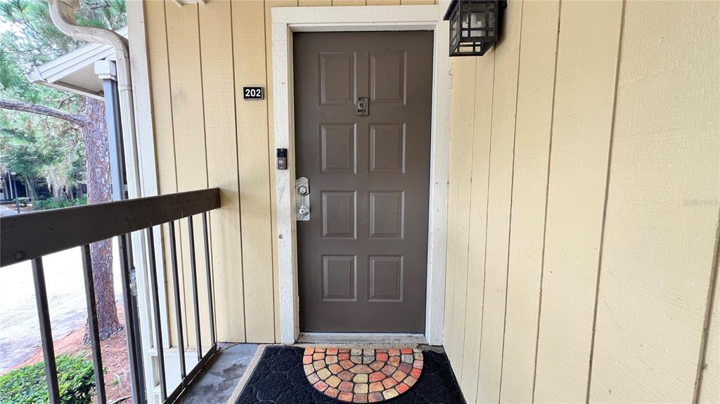 The exterior view shows a brown front door with a number 202 sign — 13289 ARBOR POINTE CIRCLE UNIT 202, TAMPA, FL