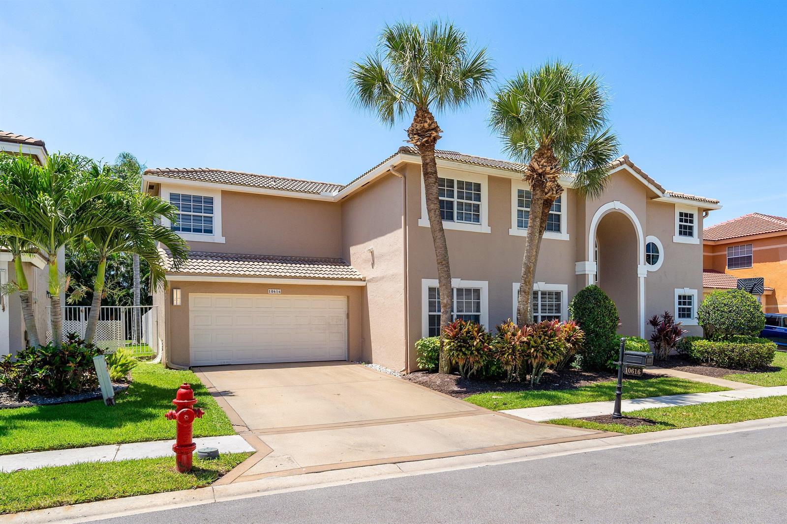 A two-story tan stucco house features a two-car garage, palm trees, and a fire hydrant — 10616 Wheelhouse Circle, Boca Raton FL 33428, BOCA RATON, FL