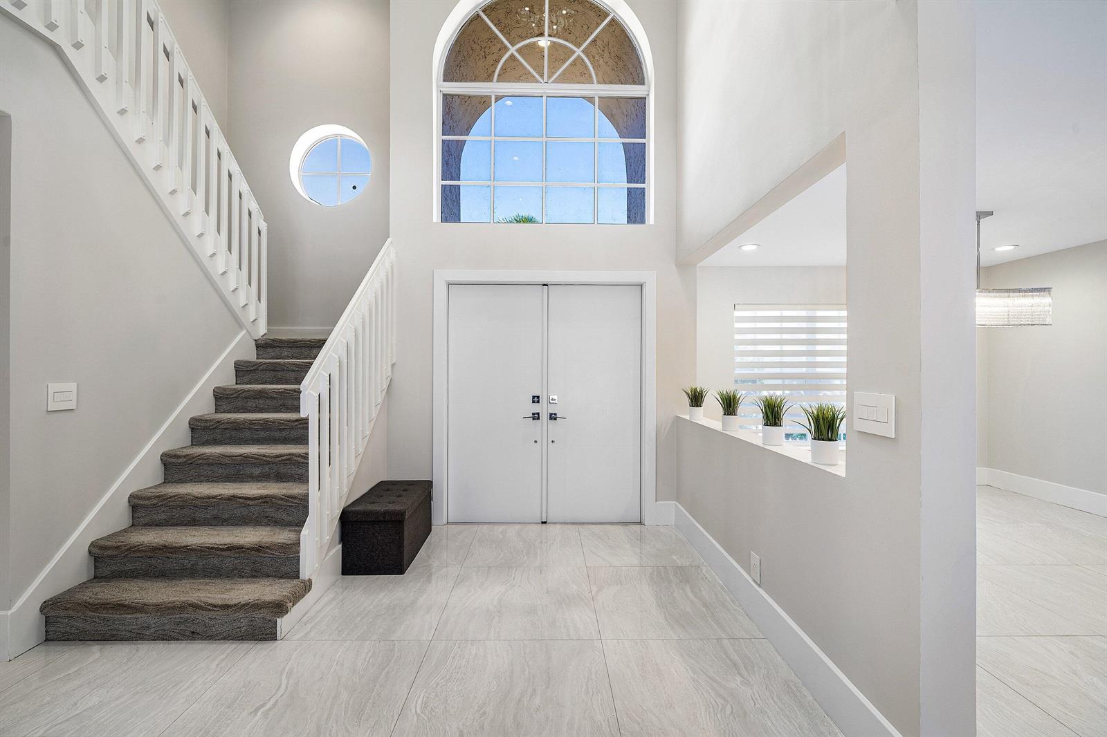 A bright entryway features a staircase, double front doors, a large arched window, and tile — 10616 Wheelhouse Circle, Boca Raton FL 33428, BOCA RATON, FL
