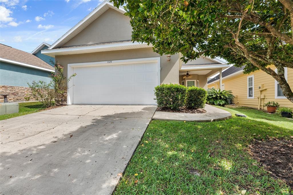 A suburban house exterior features a concrete driveway, a white garage door, and landscaping — 1125 NW 120TH WAY, GAINESVILLE, FL