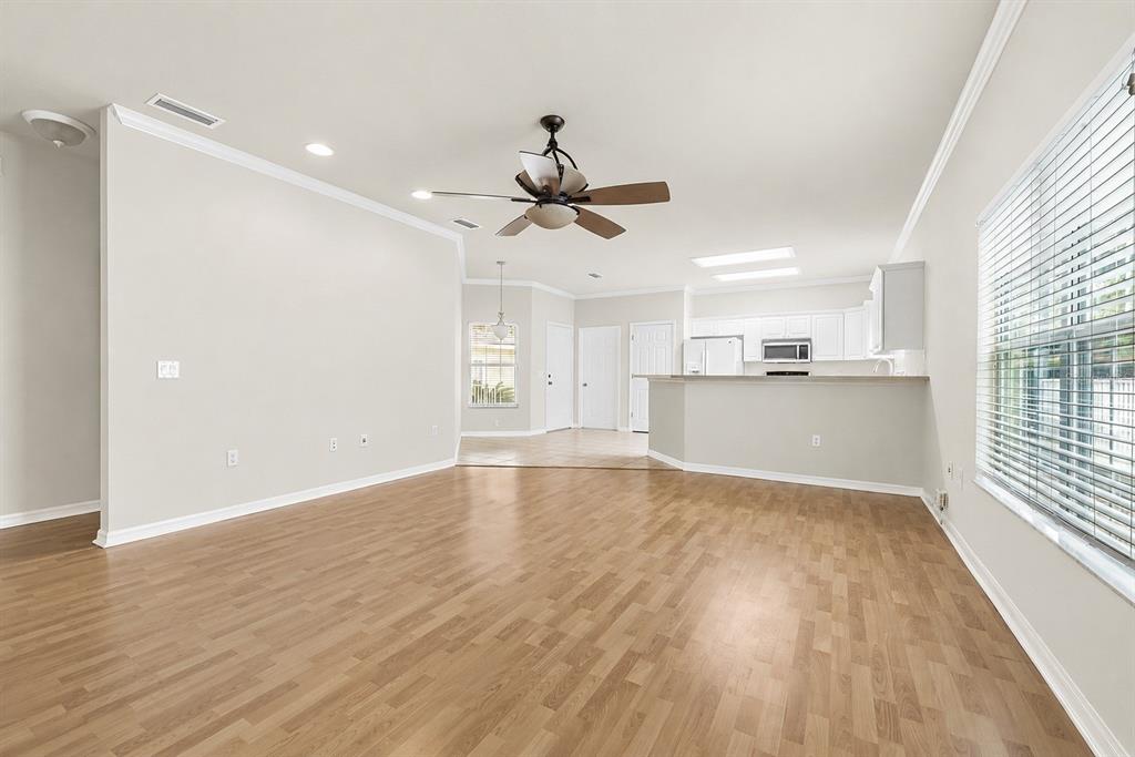 An open-concept living room with light wood-look flooring, a ceiling fan, and an adjacent kitchen — 1125 NW 120TH WAY, GAINESVILLE, FL