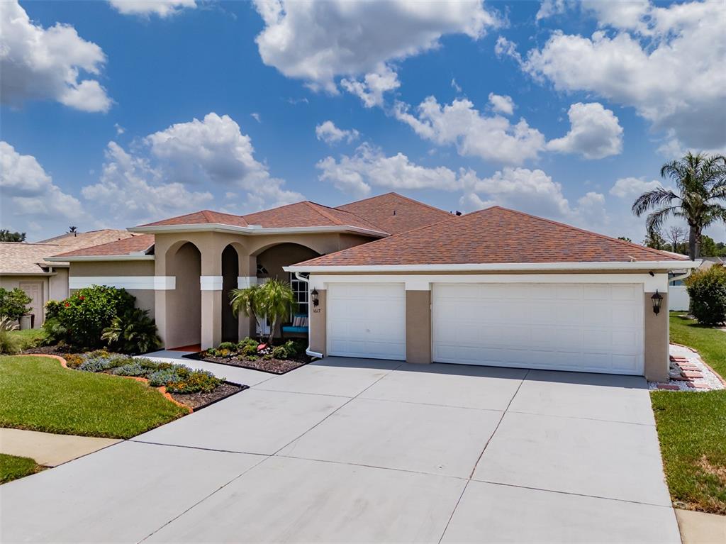 A single-story house with a two-car garage, arched entryway, and a brown shingled roof — 1617 VISTOSO LANE, SUN CITY CENTER, FL