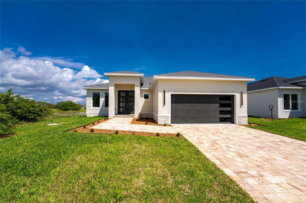 A modern single-story house features a paved driveway, a two-car garage, and a covered entryway — 205 REDWOOD ROAD, ROTONDA WEST, FL