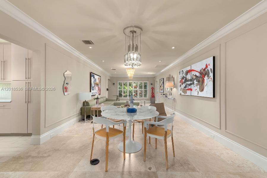 A dining area features a marble table, modern chairs, and a crystal chandelier — 830 E Dilido Dr, Miami Beach FL 33139, MIAMI BEACH, FL