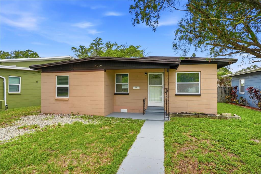 A single-story tan house with a flat roof, a concrete walkway, and a small porch — 3219 40TH STREET N, ST PETERSBURG, FL