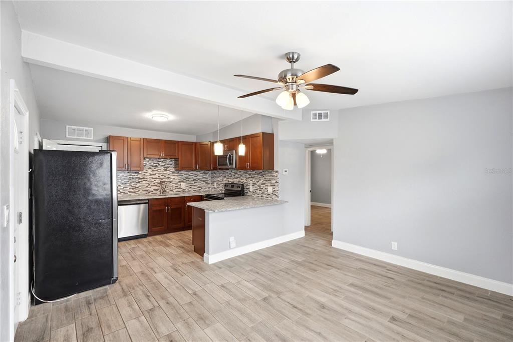 A kitchen with wood cabinets, a breakfast bar, and stainless steel appliances opens to a room — 3219 40TH STREET N, ST PETERSBURG, FL