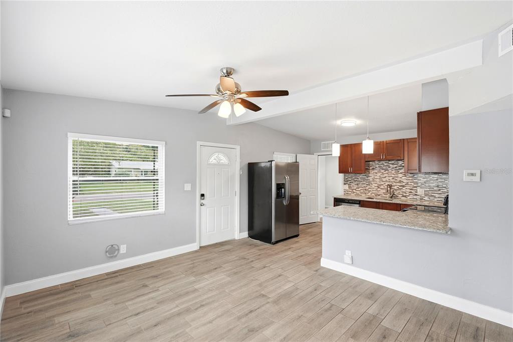 A living room with wood-look tile floors opens to a kitchen featuring granite countertops — 3219 40TH STREET N, ST PETERSBURG, FL