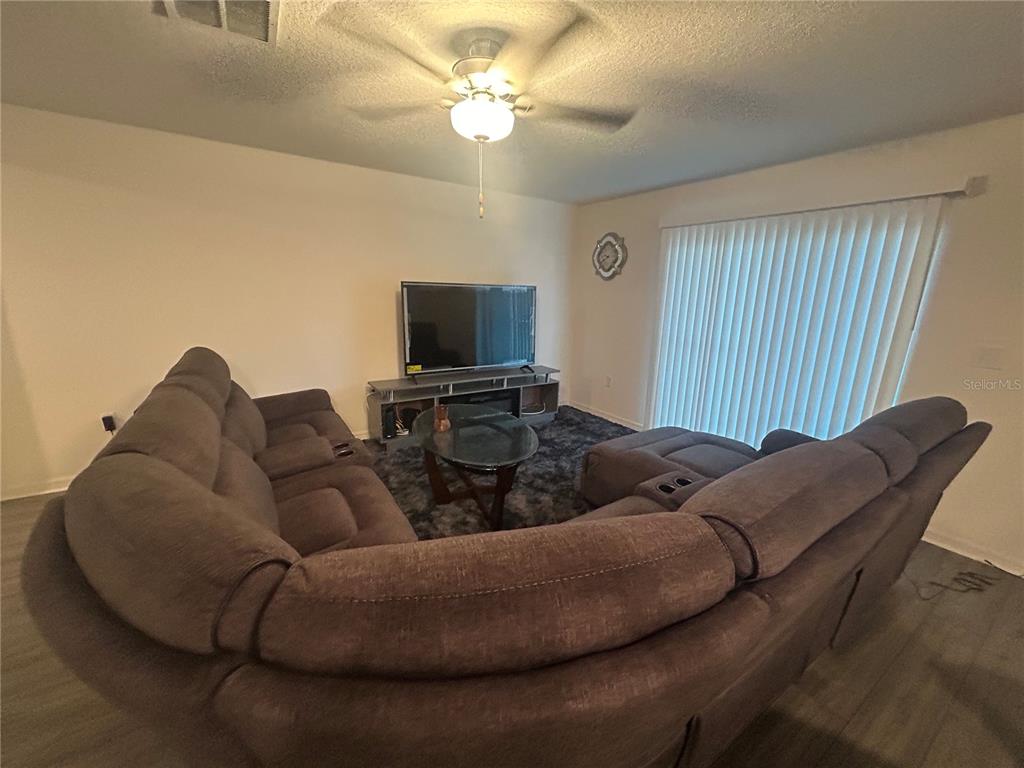 A living room features a large sectional sofa, a television on a stand, and vertical blinds — 1303 CONGO COURT, POINCIANA, FL