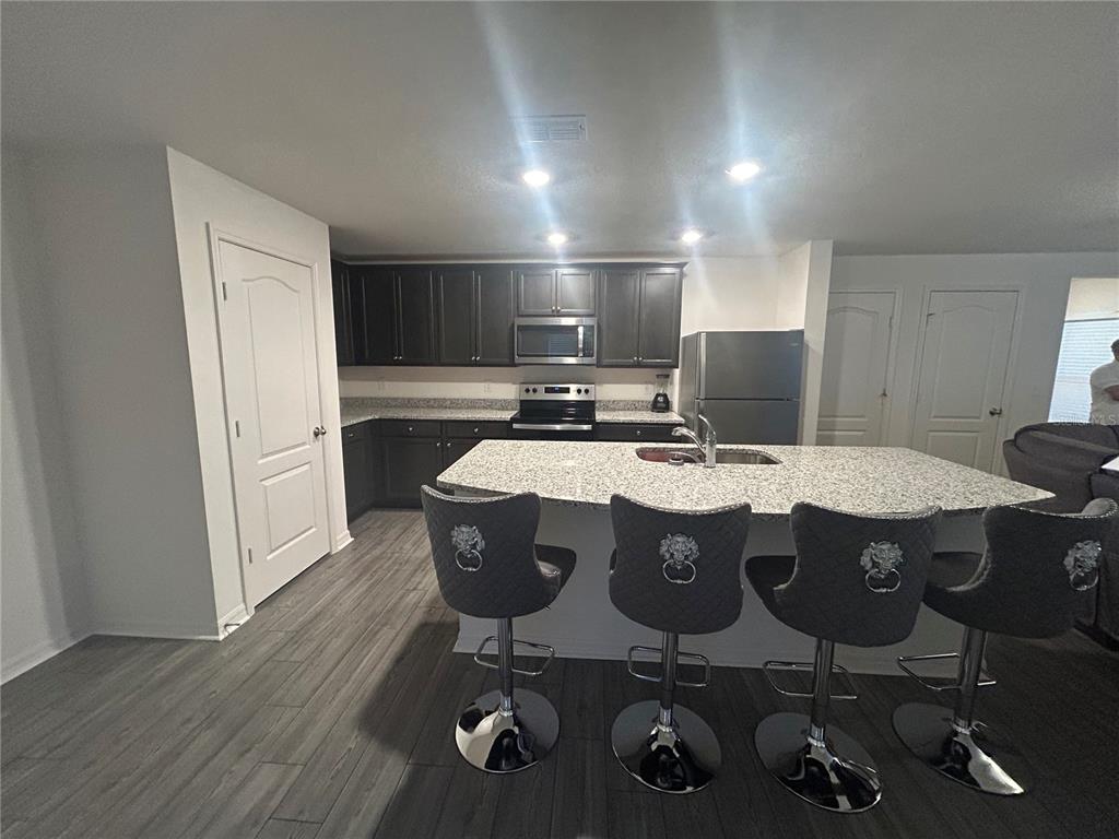 A kitchen features dark cabinets, granite countertops, a central island with bar stools, and flooring — 1303 CONGO COURT, POINCIANA, FL