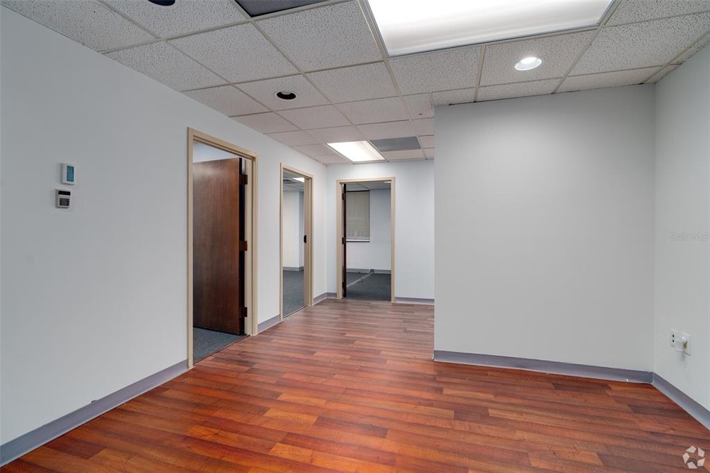 An office hallway with wood-look flooring, white walls, and three open doorways — 14 E WASHINGTON STREET, ORLANDO, FL
