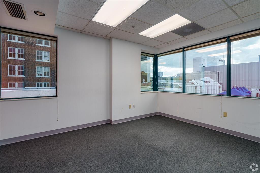 An empty office with gray carpet, white walls, and large windows overlooking a city street — 14 E WASHINGTON STREET, ORLANDO, FL