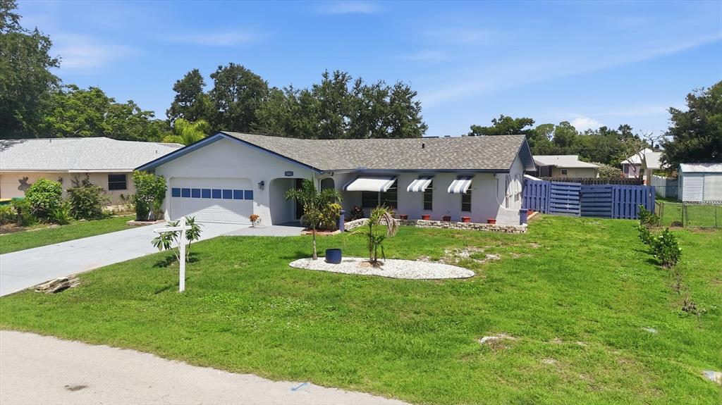 A single-story house with a white exterior, a garage, and a blue fence — 1042 MALAY TERRACE NW, PORT CHARLOTTE, FL