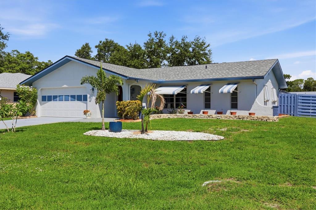 A single-story house with a white exterior, blue trim, a garage, and a front lawn — 1042 MALAY TERRACE NW, PORT CHARLOTTE, FL