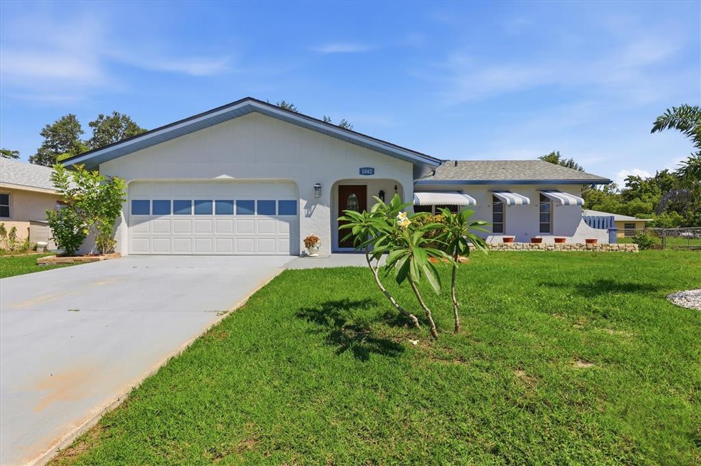 A single-story house with a white exterior, a two-car garage, and a front lawn — 1042 MALAY TERRACE NW, PORT CHARLOTTE, FL