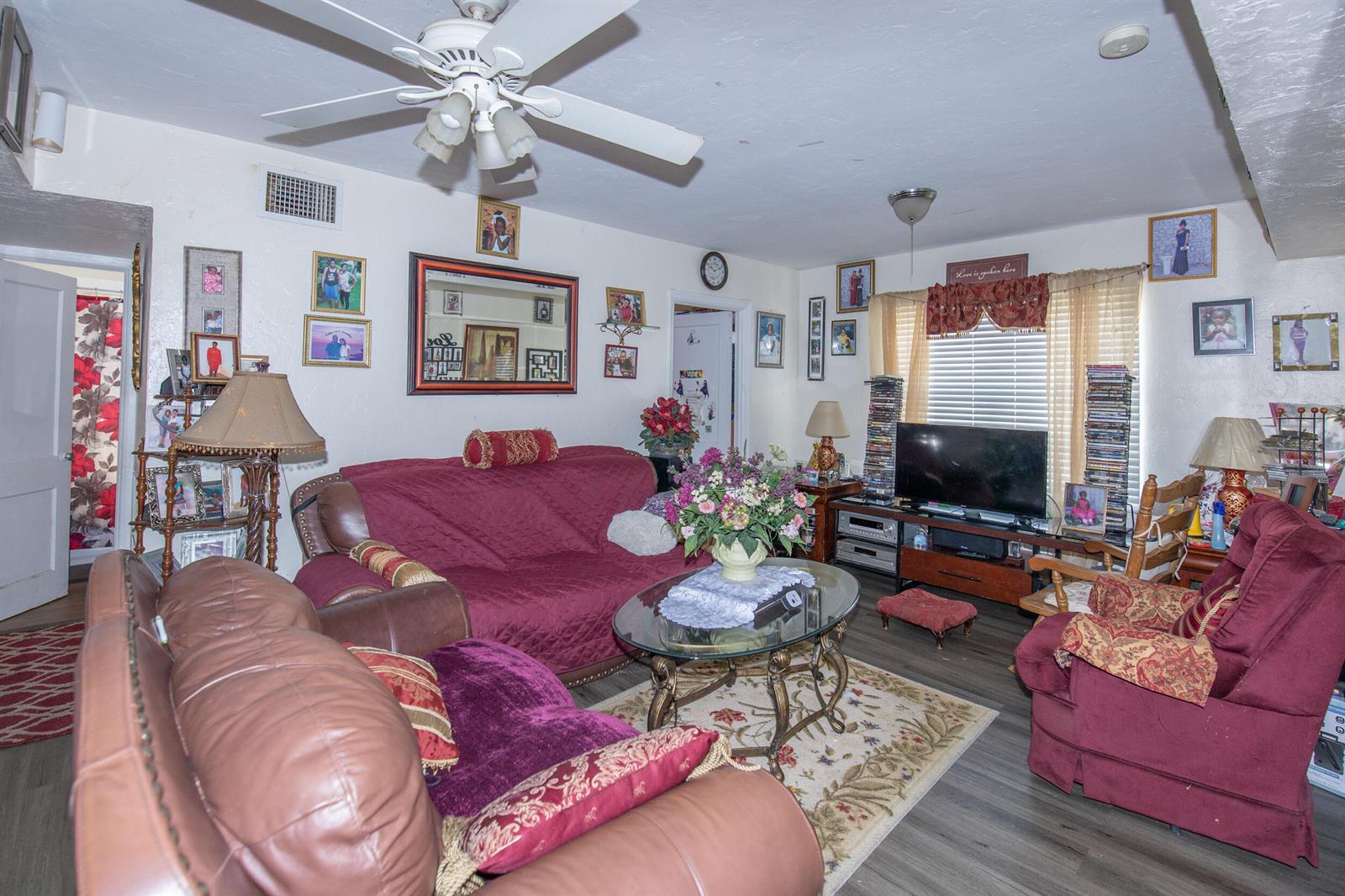 A living room features a red sofa, a matching armchair, a glass coffee table, and television — 928 S Dixie Highway, FL 33460, FL