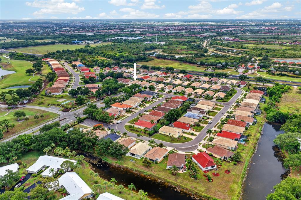 An aerial view shows a suburban neighborhood with houses, a golf course, and a canal — 318 LANGHOLM DRIVE, VENICE, FL