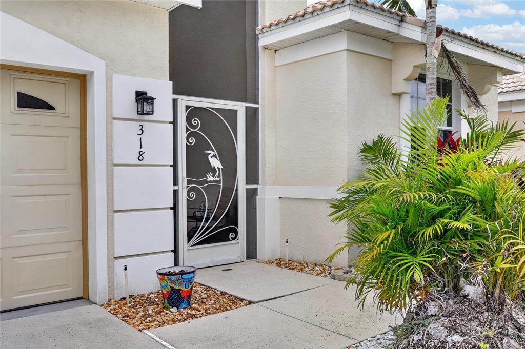 The exterior of a house features a garage, a decorative screen door, and a palm tree — 318 LANGHOLM DRIVE, VENICE, FL
