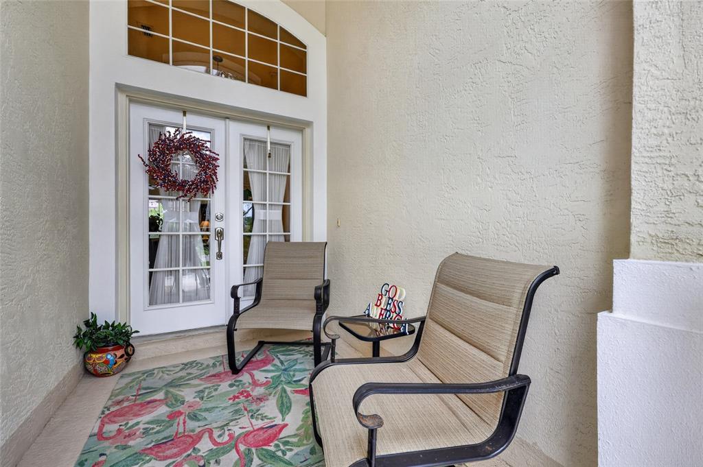 A covered patio features two chairs, a small table, and a flamingo-patterned rug — 318 LANGHOLM DRIVE, VENICE, FL