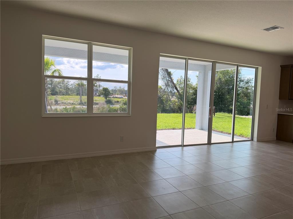 A room with tiled floors, a large window, and sliding glass doors leading to a patio — 756 FARFIELDS STREET, DELAND, FL