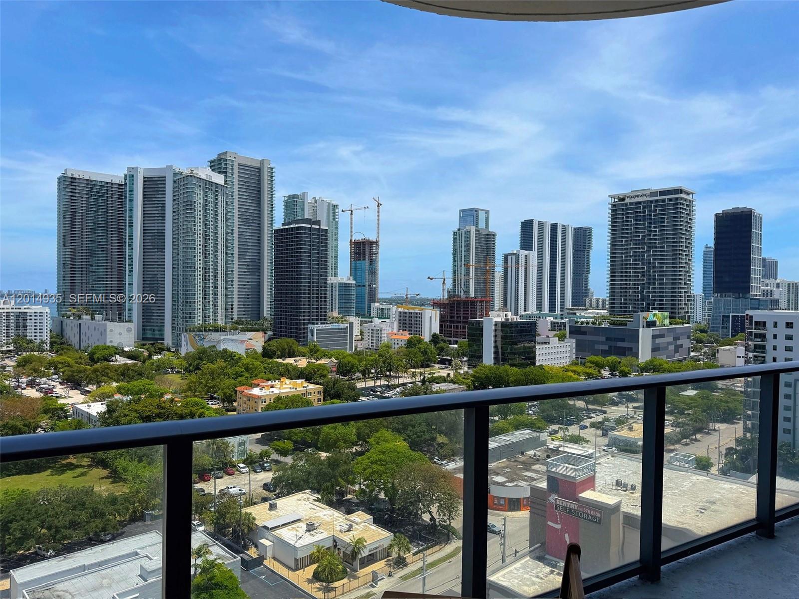 A balcony view overlooks a dense urban skyline with numerous high-rise buildings and green trees — 121 NE 34th St # 1605, Miami FL 33137, MIAMI, FL