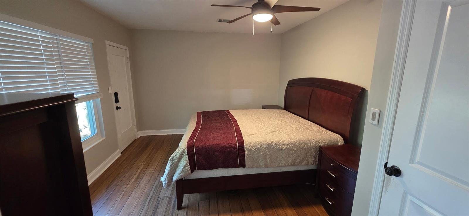 A bedroom features a wooden bed frame, a ceiling fan, and wood-look flooring — 6120 9th Avenue S, FL 33707, FL