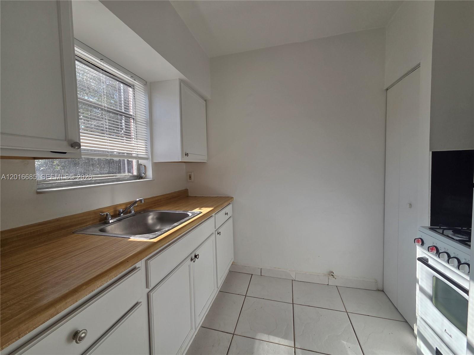 A kitchen features white cabinets, a wood-look laminate countertop, a stainless steel sink, and tile flooring — 781 SW 11th St # 3, Miami FL 33129, MIAMI, FL