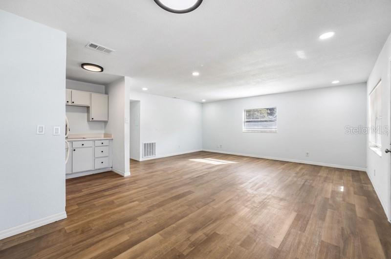 A spacious room features light-colored walls, wood-look flooring, recessed lighting, and a small kitchenette area — 1132 AUBURN STREET, CLEARWATER, FL
