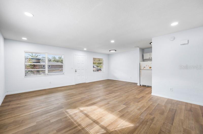 An open-concept living area features light-colored walls, wood-look flooring, recessed lighting, and a refrigerator — 1132 AUBURN STREET, CLEARWATER, FL