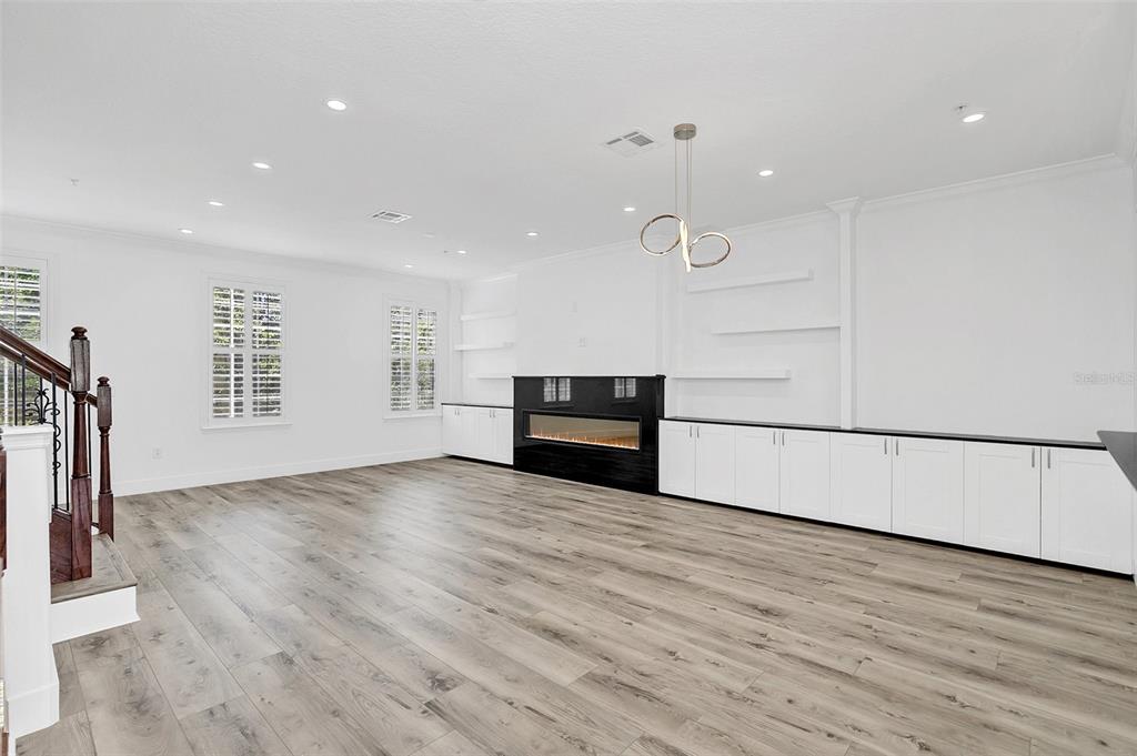 A living room features light wood-look flooring, white cabinetry, floating shelves, and a linear fireplace — 1579 CHATFIELD PLACE, ORLANDO, FL