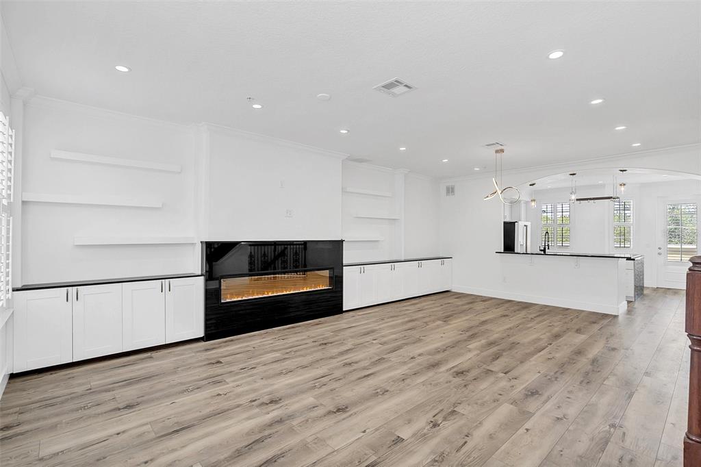 A living room features a black fireplace, white built-in cabinetry, floating shelves, and wood flooring — 1579 CHATFIELD PLACE, ORLANDO, FL