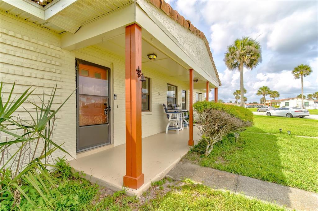 A covered porch with wooden posts leads to a front door of a brick house — 232 NORTHSHORE DRIVE UNIT A & #B, ORMOND BEACH, FL