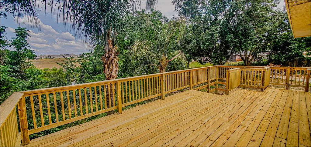 A wooden deck overlooks a lush green landscape with trees and a distant field — 2614 CREST DRIVE, HAINES CITY, FL