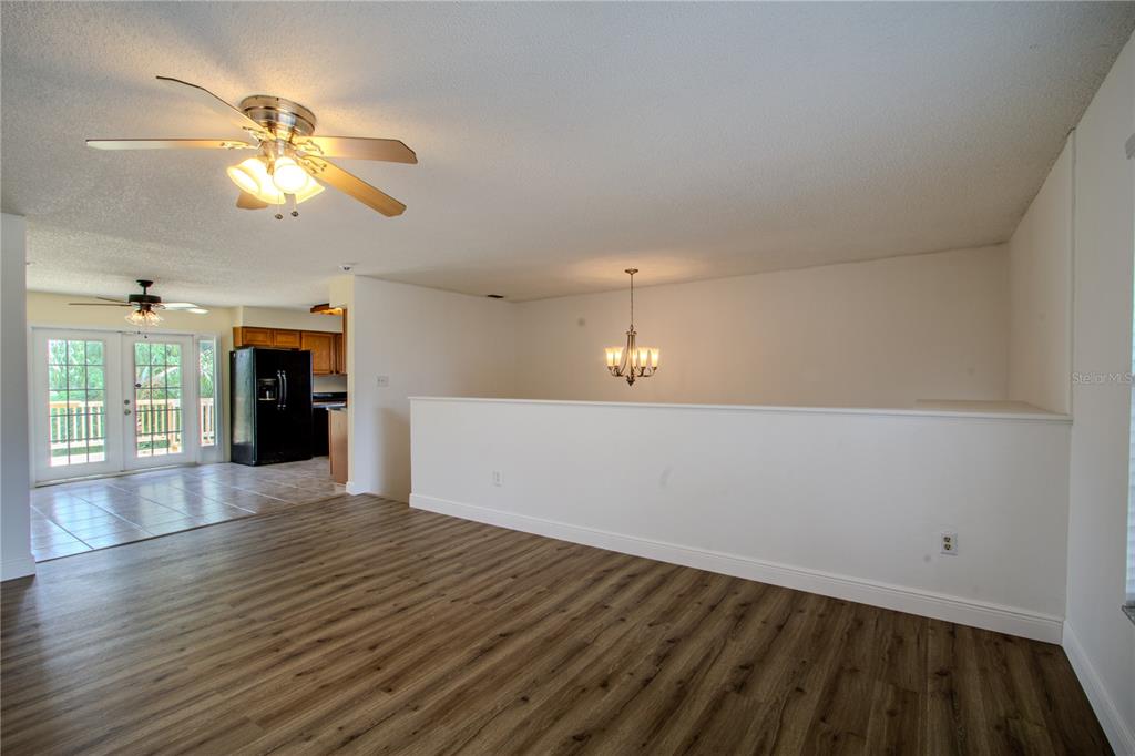 A living room with wood-look flooring, a ceiling fan, and a half-wall overlooking a dining area — 2614 CREST DRIVE, HAINES CITY, FL