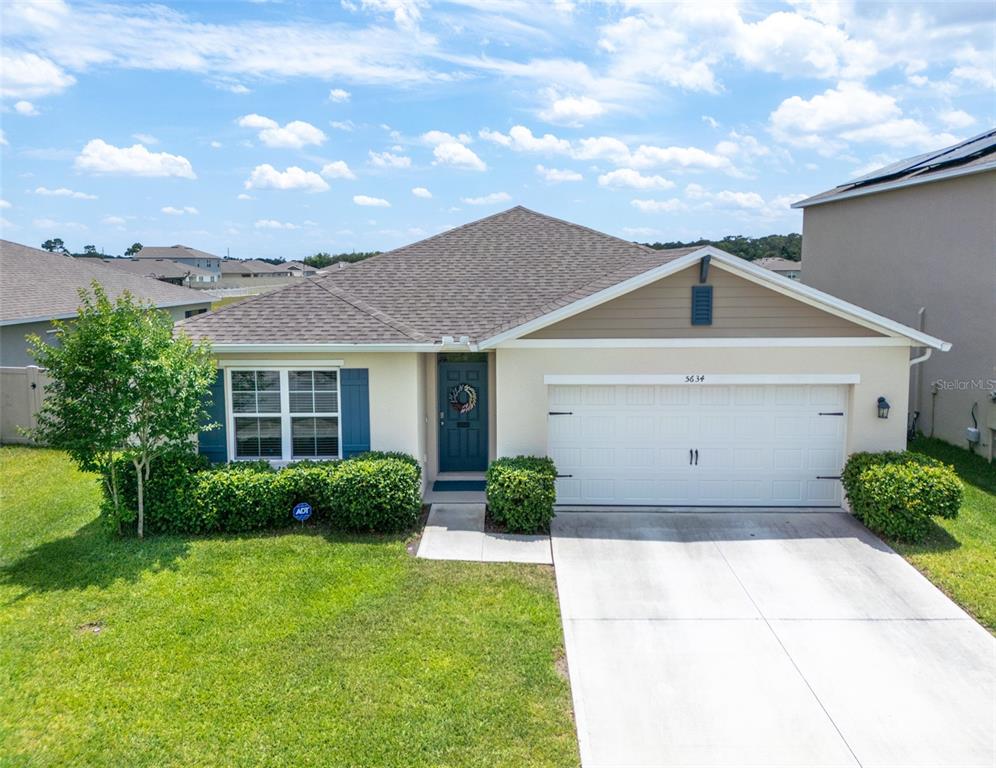 A single-story house with a beige stucco exterior, blue shutters, and a two-car garage — 5634 WINONA DRIVE, ST CLOUD, FL