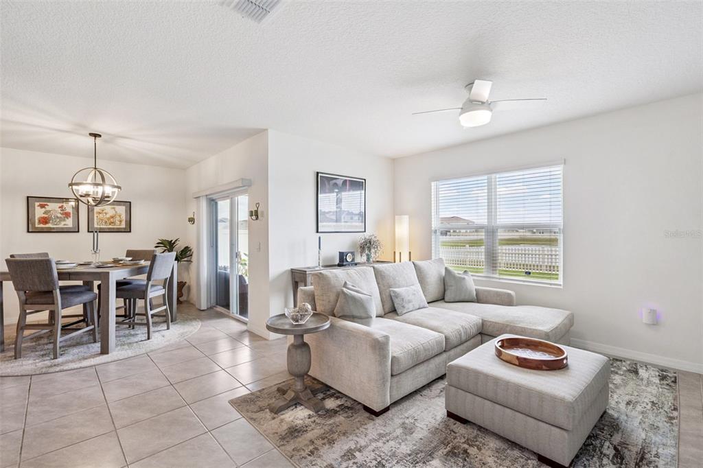 A living room with a sectional sofa and a dining area with a round chandelier — 5634 WINONA DRIVE, ST CLOUD, FL