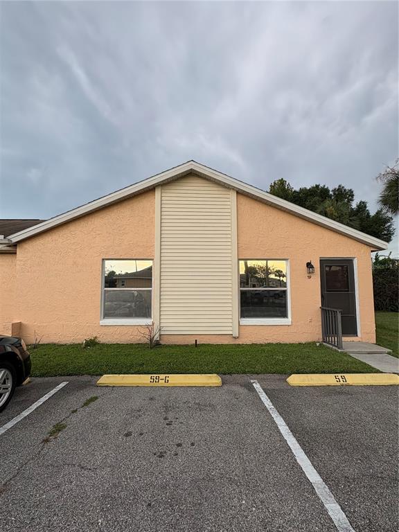 A peach-colored single-story building exterior features two windows, a front door, and parking spaces — 59 E COUNTRY COVE, KISSIMMEE, FL