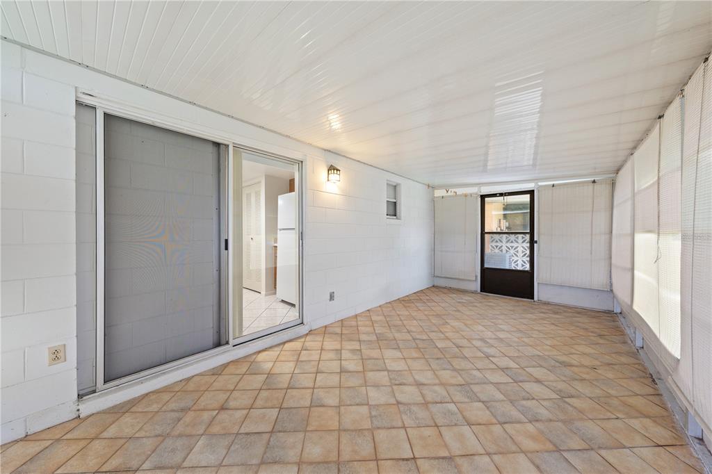A sunroom with tiled flooring, white block walls, a sliding glass door, and screen windows — 59 E COUNTRY COVE, KISSIMMEE, FL
