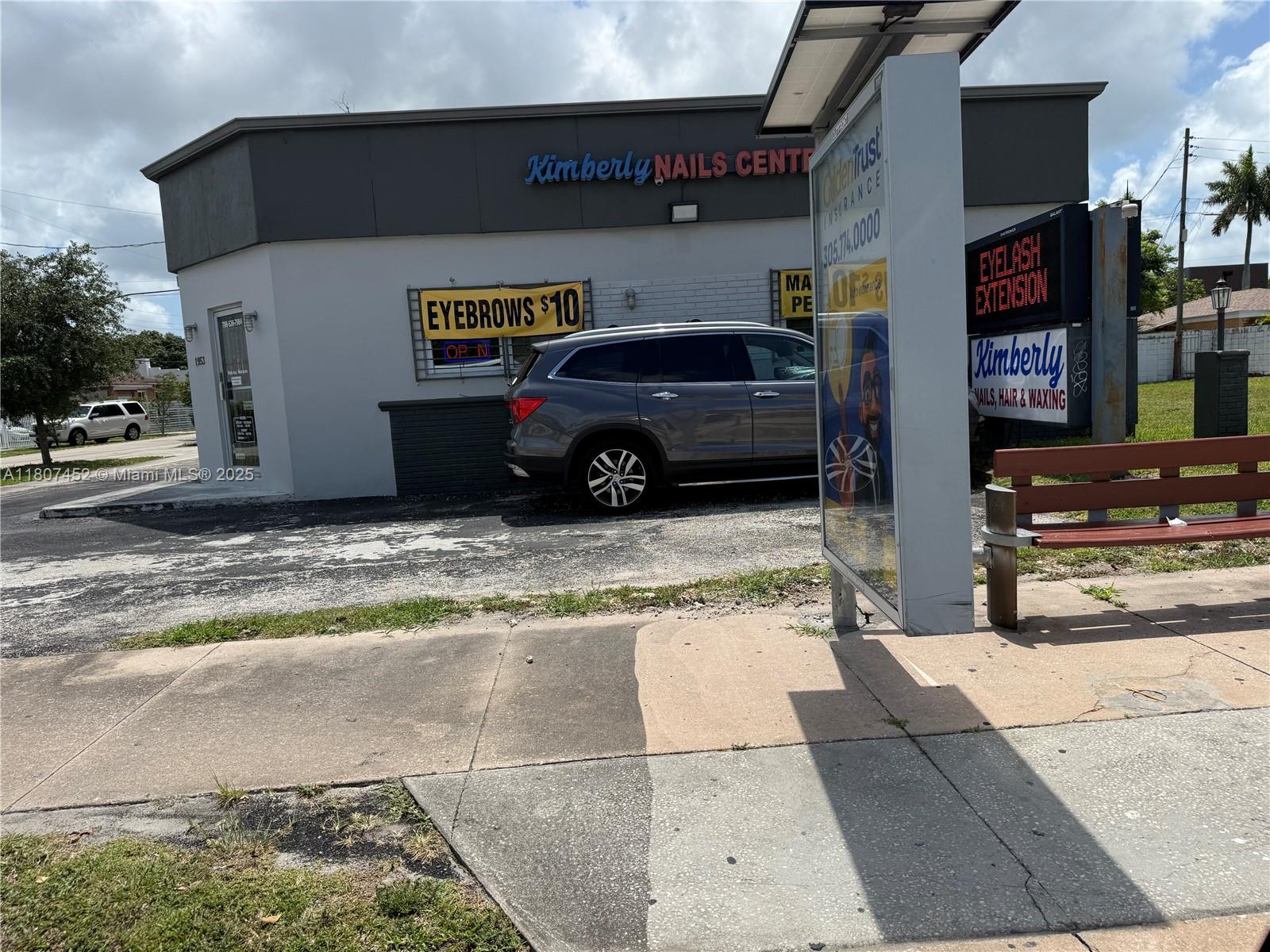 A gray SUV is parked in front of a nail salon with an outdoor bench — 1953 SW 27th Ave, Miami FL 33145, MIAMI, FL